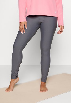 Leggings cinzentos com riscas e um design ajustado, combinados com uma blusa de mangas longas rosa, expostos sobre um tapete de yoga.