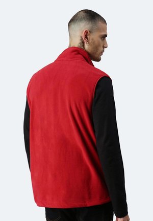 Gilet di pile rosso con colletto alto, design senza maniche, texture morbida e vestibilità rilassata, indossato sopra una maglietta nera a maniche lunghe.