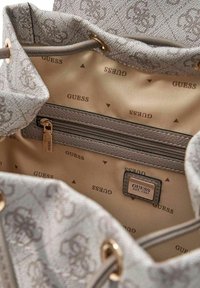 Sac cabas à motifs gris avec extérieur en textile, ferrures dorées et intérieur beige affichant le logo "GUESS" ainsi qu'une poche zippée.