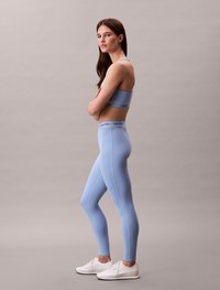 Light blue activewear set, featuring a crop top with a logo band and high-waisted leggings. Smooth texture, simple design, and athletic fit.