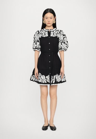Robe noire avec broderie florale blanche, manches bouffantes, boutonnière à l'avant, taille ceinturée et ourlet festonné. Texture lisse et design à mi-mollet.