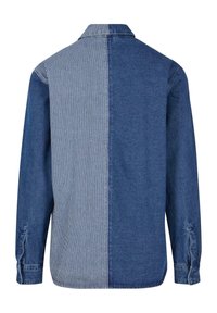 Chemise en denim à manches longues avec un dos fendu, présentant un bleu uni à droite et des rayures verticales blanches et bleues à gauche.