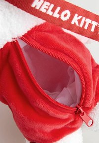 Röd plyschväska med en mjuk textur, som har en dragkedja och en vit foder, accentuerad med ett rött Hello Kitty-rep.