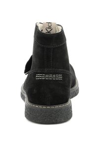 Botas ankle de ante negro con suela texturizada, que presentan un diseño cosido en la parte trasera y una etiqueta de marca en el collar.