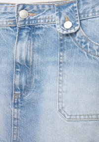 Jeans in denim blu chiaro con una finitura sbiadita, dotati di accessori in argento, design a cinque tasche e cuciture arancioni a contrasto.