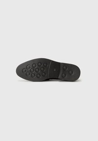 Black shoe sole with a smooth finish, featuring circular rubber grips for traction and size marking of 41.