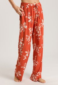 Rode bloemige broek met een losse pasvorm, gemaakt van lichtgewicht materiaal. Bevat witte bladmotieven, een elastische tailleband en zijzakken.