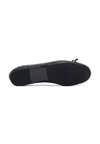 Zapato plano negro con un upper texturizado que recuerda a un material trenzado. Cuenta con un tacón negro liso y un suela de goma con un patrón.