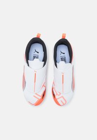 Chaussures Puma à enfiler blanches avec des accents orange. Tige en synthétique lisse, intérieur rembourré noir et semelle en caoutchouc avec grip texturé.