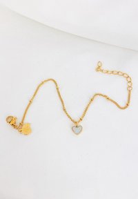 Pulsera de cadena de oro con un encantador charm en forma de corazón y un charm de concha marina, con eslabones texturizados y un cierre de langosta seguro.