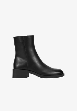 Bottine noire en cuir avec un petit talon carré et un bout arrondi lisse, vue latérale sur fond blanc.