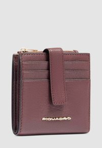 Portafoglio in pelle bordeaux con più scomparti per carte, un comparto con zip e chiusura a scatto. Presenta dettagli del logo in oro.