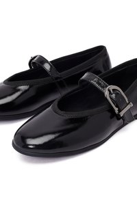 Zapatos Mary Jane de charol negro con punta redonda, correa elástica y detalle de hebilla metálica. Textura suave y tacón bajo.