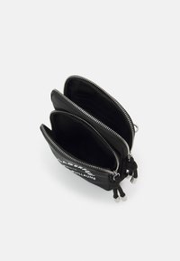 Czarna skórzana torba z trzema zasuwanymi komorami, srebrnymi elementami i gładką fakturą, z logo nadrukowanym z jednej strony.