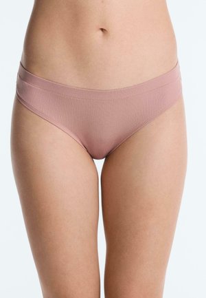 Femme portant un sous-vêtement bikini côtelé mauve clair, montrant la taille jusqu'aux cuisses supérieures sur un fond uni clair.