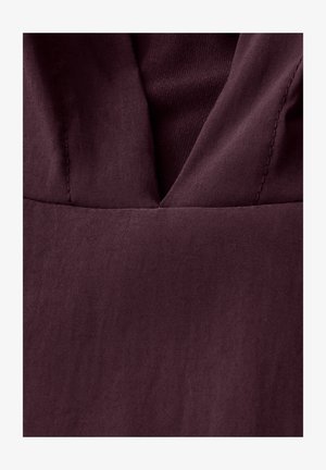 Bordeaux stof med en glat tekstur og dyb V-udskæring, der viser subtile syninger ved sømmene.