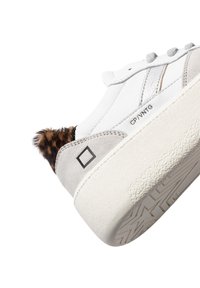 Hvide lædersneakers med grå ruskindsdetaljer og en leopardmønstret pelsdetalje ved hælen. Har en tekstureret gummisål og flade snørebånd.