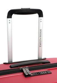 Červený tvrdý kufr s černou teleskopickou rukojetí, vybavený dvojitými zipy, integrovaným kombinovaným zámkem a texturovaným povrchem.