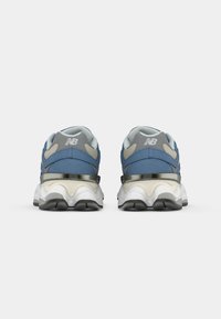 Pair of blue and gray New Balance sneakers shown from the rear with white midsoles and black outsole accents on a white background.