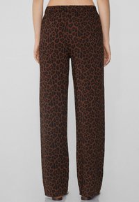 Hnědé a černé kalhoty s leopardím potiskem, široké nohavice s elastickým pasem a hladkou texturou, s rovnými liniemi a splývavým designem.