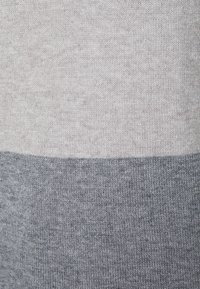 Maglione a maglia con un design a blocchi di colore, caratterizzato da sezioni grigio chiaro e grigio scuro, che mostra una trama morbida e una cucitura uniforme.