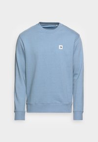 Jasnoniebieska bluza wykonana z miękkiego materiału. Posiada okrągły dekolt, długie rękawy, ściśnięte mankiety oraz małe prostokątne logo na piersi.