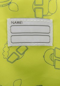 Gult tyg med ett mönster av blå konturer av olika former. En vit etikett med två rader för namn är sydd vid kanten.