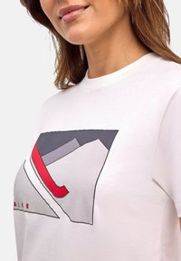 Weißes Baumwoll-T-Shirt mit einem geometrischen Design in Grau, Rot und Schwarz. Der Halsausschnitt ist gerippt, und der Druck befindet sich zentriert auf der Vorderseite.