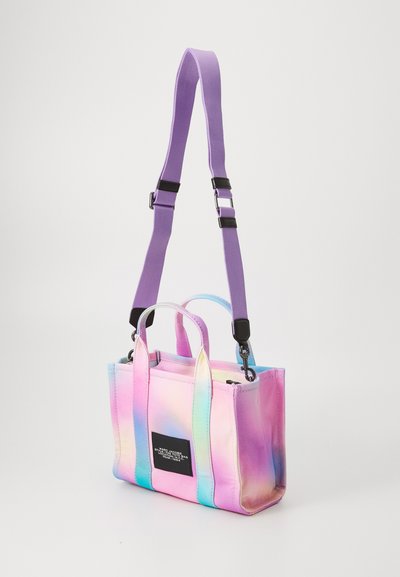 Väike kott iridescentses roosa ja sinises kangas lavendlivärvi rihmaga, topeltkäepidemetega, ristküliku kuju ja musta logosildiga.