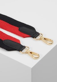 Cinghia intrecciata nera e rossa con dettagli in pelle, dotata di ganci in metallo dorato per attacchi. Design piatto e testurizzato.