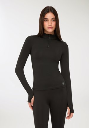 Maglietta nera a maniche lunghe con zip, realizzata in materiale elastico, dotata di collo a finta e fori per il pollice, con un dettaglio del logo sull'orlo.
