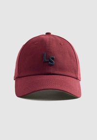 Piros pamut baseball sapka ívelt napellenzővel és sötétkék hímzett "LS" logóval az elején; varrott díszítésekkel és szellőzőlyukakkal rendelkezik.