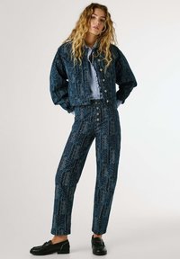 Denim jacket and pants set in dark blue with leaf pattern, featuring button closures, wide sleeves, and straight-leg cut. Black loafers complete the look.