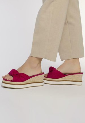 Sandales compensées fuchsia avec un dessus en tissu noué, une semelle intermédiaire à texture paille et une semelle extérieure en caoutchouc blanc, découvrant les orteils et la cheville.