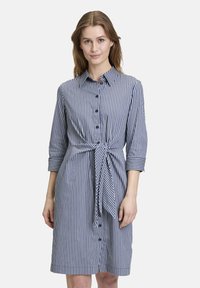 Abito a righe in blu navy e bianco, con una chiusura a bottoni, colletto, maniche a trequarti e un dettaglio in vita annodato. Tessuto dalla texture liscia.