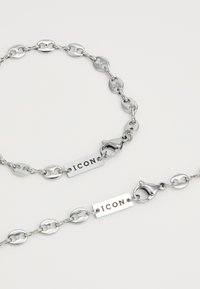 Strieborný reťazový náramok s oválnymi článkami, textúrovaným povrchom a gravírovanou obdĺžnikovou tabuľkou s nápisom "ICON", so sponou typu lobster.