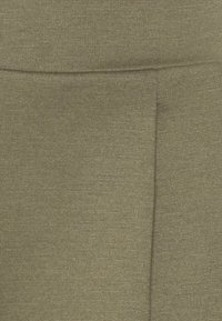 Gros plan sur un tissu vert olive avec une couture visible et une texture côtelée subtile.