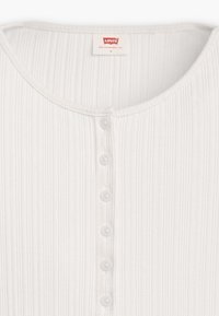 Weißes gestreiftes Stoffhemd mit rundem Ausschnitt und sechs kleinen Knöpfen an der Vorderseite, mit einem Levi's-Label am Kragen.