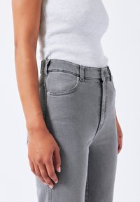 Grijze denim broek met een hoge taille, voorzien van een vijf-pocket ontwerp, standaard klinknagels en een licht taps toelopende pijp. Zichtbare textuur van de stof.