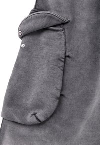 Sudadera gris con una manga doblada y un detalle de botón, de textura suave. La tela parece blanda y cálida, adecuada para un estilo casual.