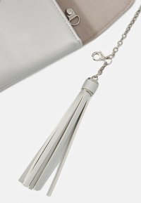 Sac à main en simili cuir argenté avec une bandoulière chaîne et un accent à pompon. Comprend une fermeture à pression magnétique et une doublure intérieure lisse.