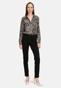 Zwart-wit patroon lange mouw blouse met kraag, gecombineerd met zwarte slim-fit broek en witte puntige hakken.