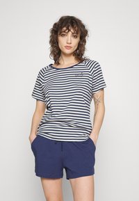 Camiseta de rayas en azul marino y blanco con cuello redondo, combinada con pantalones cortos azul marino. La tela parece suave y el ajuste es casual.