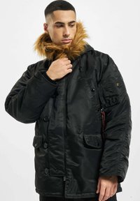 Schwarze isolierte Jacke mit Kunstpelzkragen, mehreren Taschen, Druckknöpfen und robustem Stoff; lange Ärmel und schlankes Design.