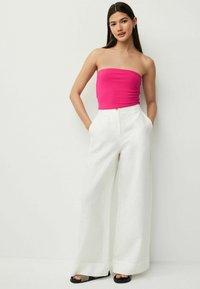 Rozā strapless tops, kas kombinēts ar platām baltām biksēm. Bikses ir aprīkotas ar sānu kabatām un izstrādātas atbilstoši figūrai. Melni sandalēm pabeidz kopskatu.