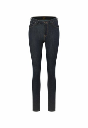 Mørkeblå skinny jeans lavet af denim. Har fem lommer, lynlås og kontrastfarvet orange syninger langs sømmene. Glat overflade generelt.