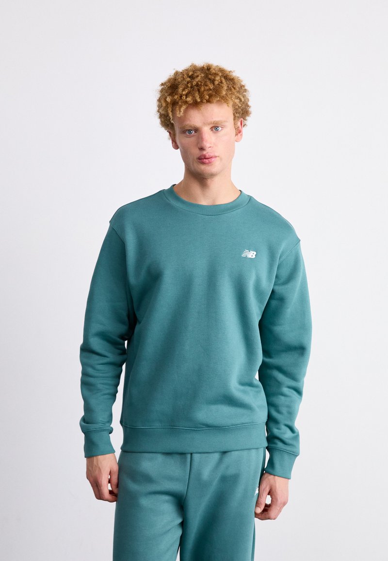 Teal katoenen sweatshirt met een ronde hals en geribde manchetten, met een klein wit logo op de linkerkant van de borst. Glad textuur, losse pasvorm.