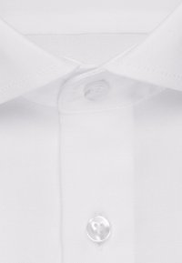 Colletto di camicia bianca in cotone con un singolo bottone di plastica trasparente. Texture liscia, bordi cuciti con cura e punte del colletto ben definite.