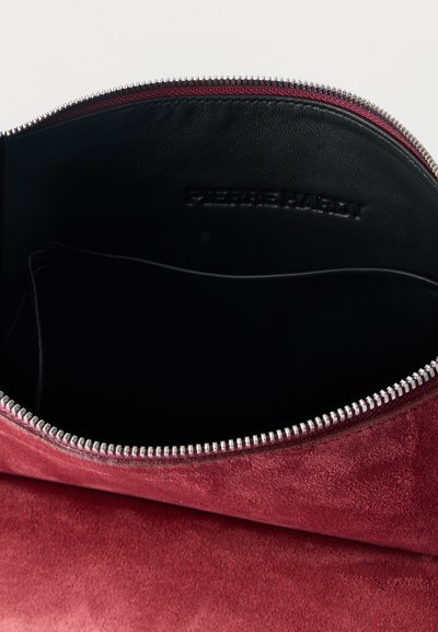 Ανοιχτό κόκκινο σουέτ πουγκί που δείχνει το μαύρο εσωτερικό από δέρμα, με φερμουάρ από ασημί μέταλλο και μια εσωτερική τσέπη με άνοιγμα.