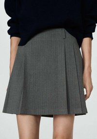 Falda plisada gris con rayas verticales, hecha de tejido entrelazado, que presenta una cintura plana y un diseño estructurado.